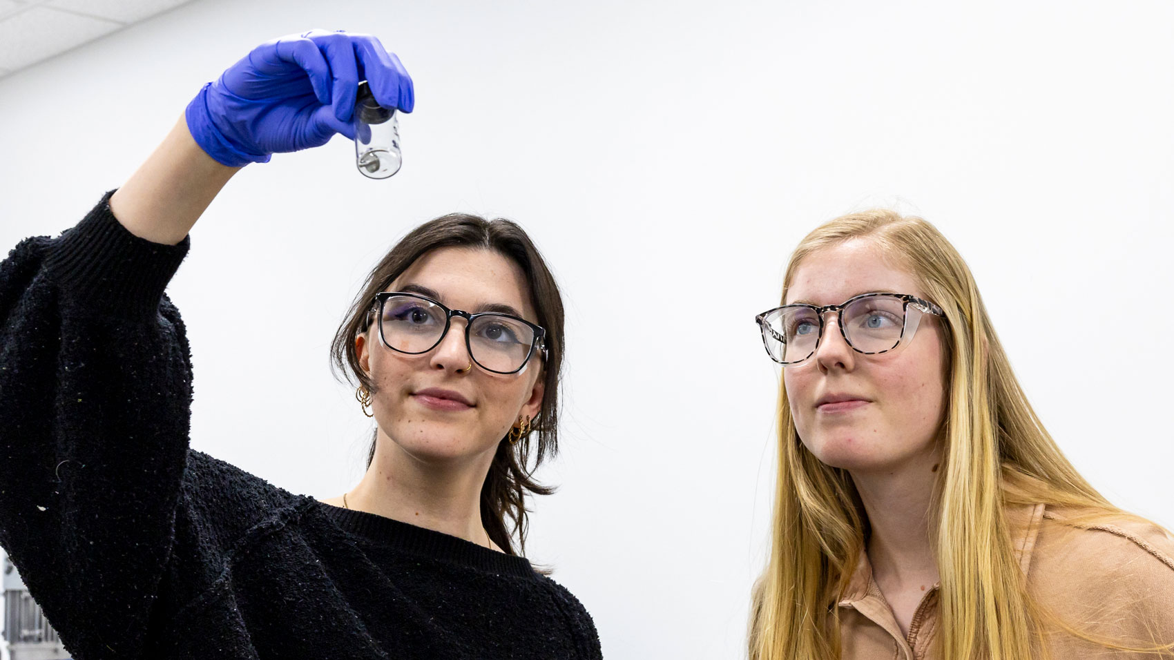 Two women with glasses looking at a piece of nanotube